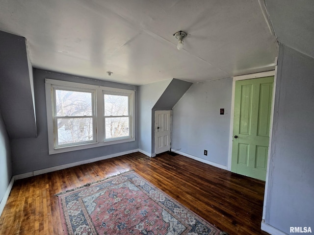 additional living space featuring vaulted ceiling and dark hardwood / wood-style flooring