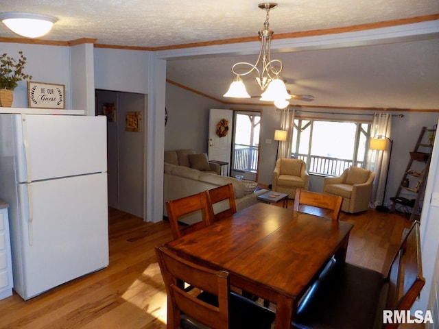 dining space with crown molding, an inviting chandelier, a textured ceiling, and light hardwood / wood-style floors