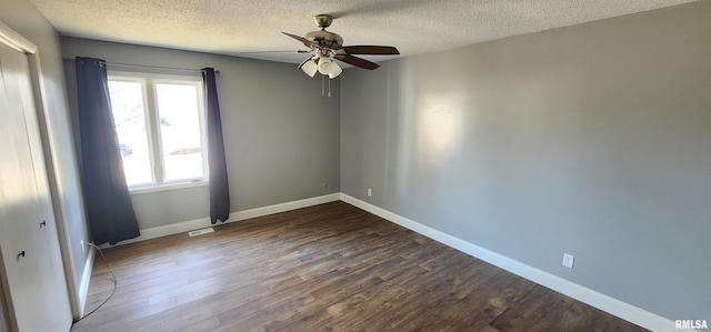 unfurnished room featuring dark hardwood / wood-style flooring, ceiling fan, and a textured ceiling