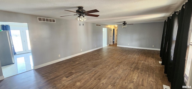 empty room featuring ceiling fan, dark wood-type flooring, and a textured ceiling