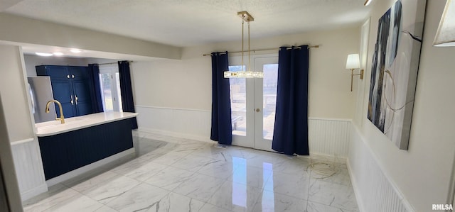 entrance foyer featuring sink, an inviting chandelier, a textured ceiling, and french doors