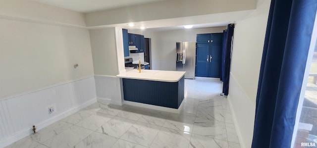 kitchen with stainless steel appliances, blue cabinetry, sink, and kitchen peninsula