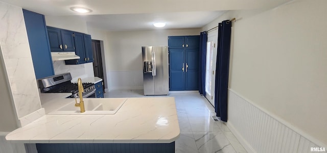 kitchen with blue cabinetry, stainless steel appliances, and light stone countertops