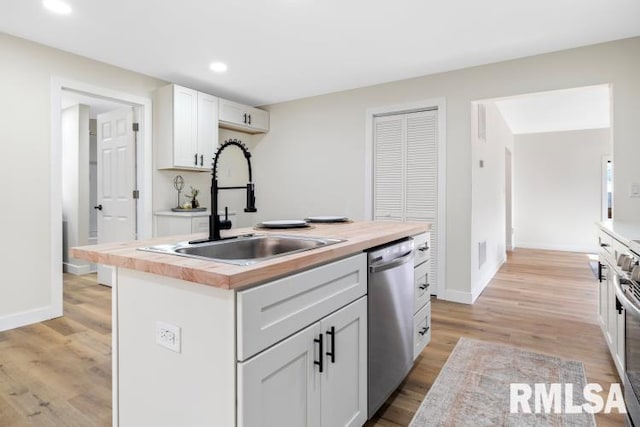 kitchen with wood counters, sink, dishwasher, an island with sink, and white cabinets