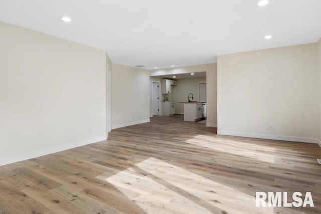 unfurnished living room with sink and light hardwood / wood-style flooring