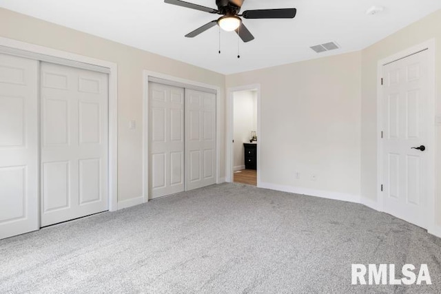 unfurnished bedroom featuring ceiling fan, light carpet, and two closets