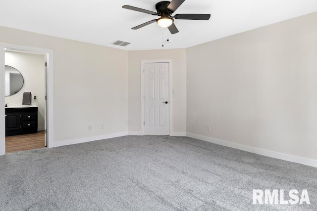 unfurnished bedroom with ceiling fan, ensuite bath, and carpet floors