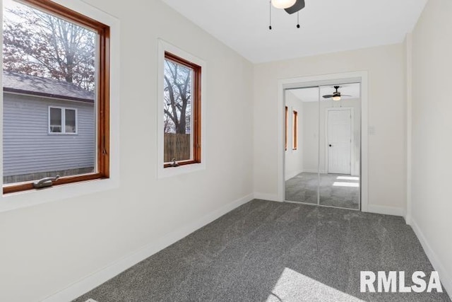 spare room with ceiling fan and dark carpet