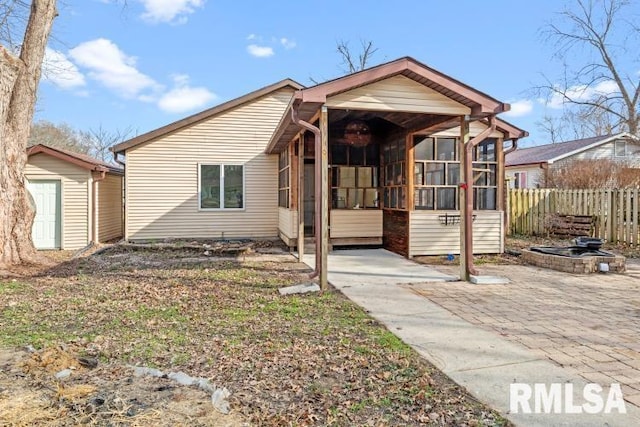 bungalow-style home with a storage shed, a patio area, and a sunroom