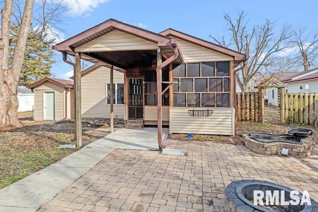 rear view of house featuring a storage shed, a sunroom, and a patio area