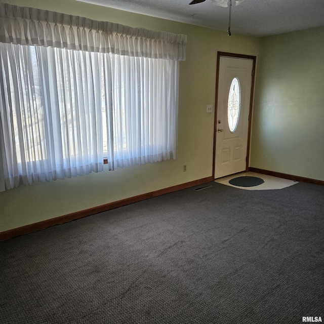 entryway with a wealth of natural light, ceiling fan, and carpet flooring