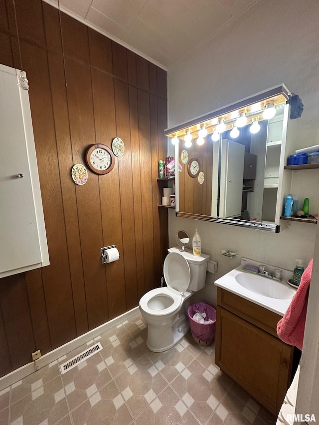 bathroom with vanity, wood walls, and toilet