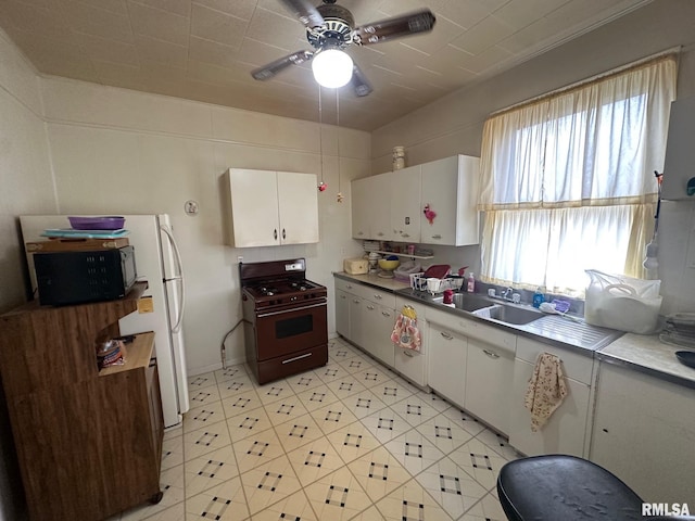 kitchen featuring sink, range with gas stovetop, white cabinets, and white fridge