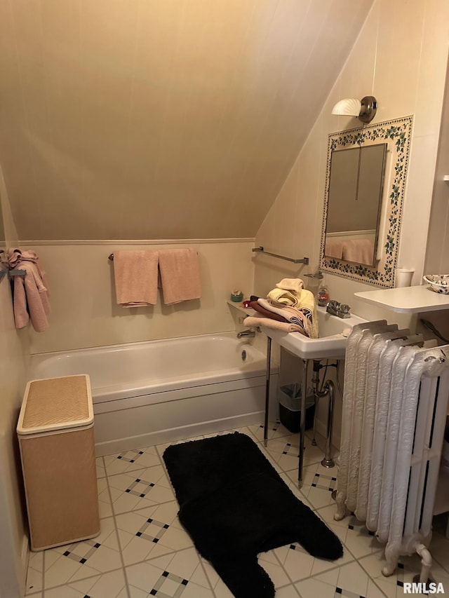 bathroom featuring vaulted ceiling, a bathing tub, radiator, and tile patterned flooring