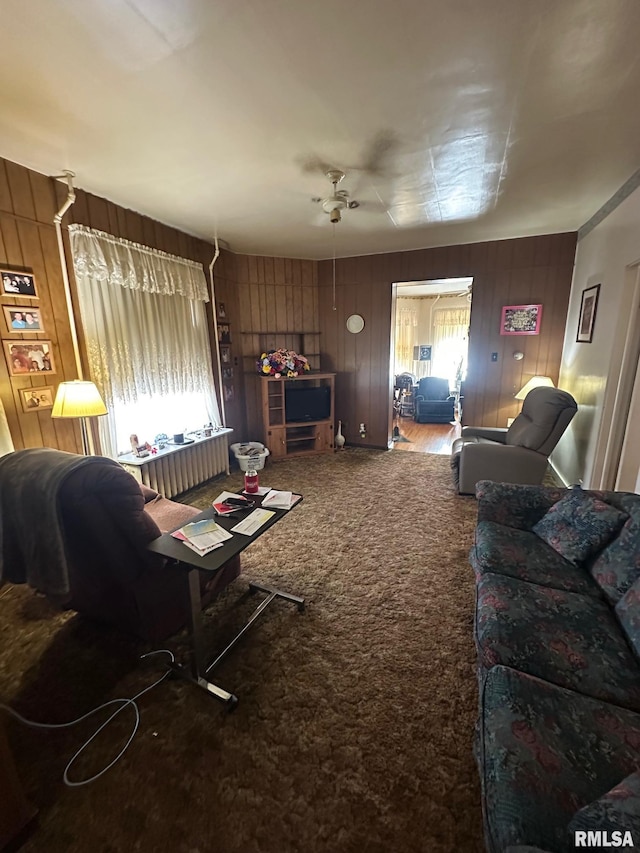 carpeted living room featuring radiator and wooden walls