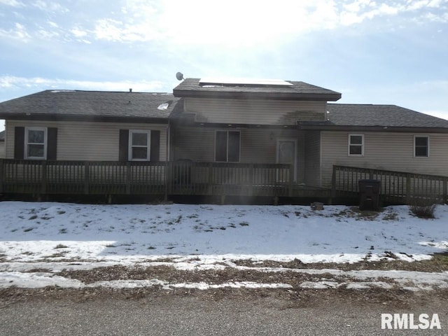 snow covered rear of property with a wooden deck