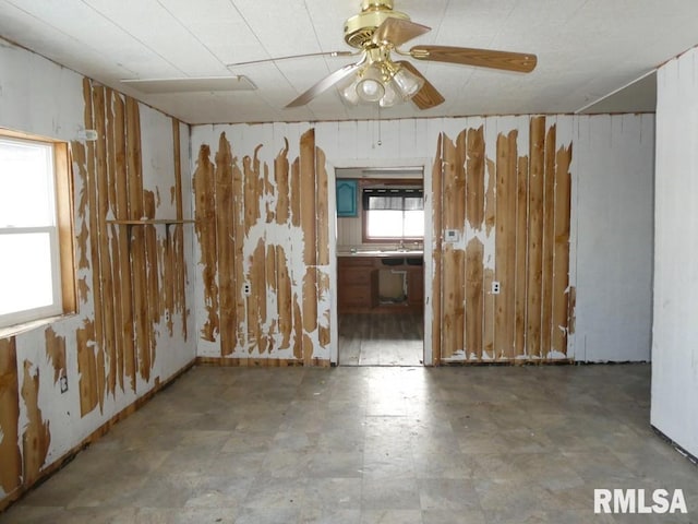 spare room featuring ceiling fan and wooden walls