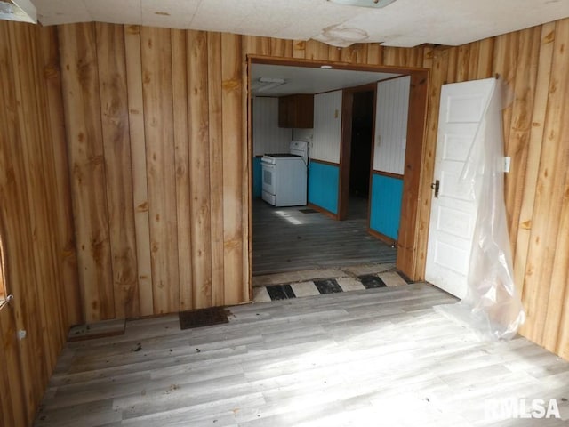 empty room with light wood-type flooring and wood walls