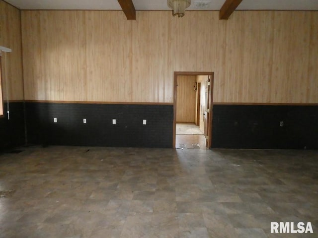 empty room featuring wooden walls and beam ceiling