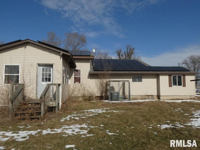 snow covered rear of property with cooling unit and solar panels