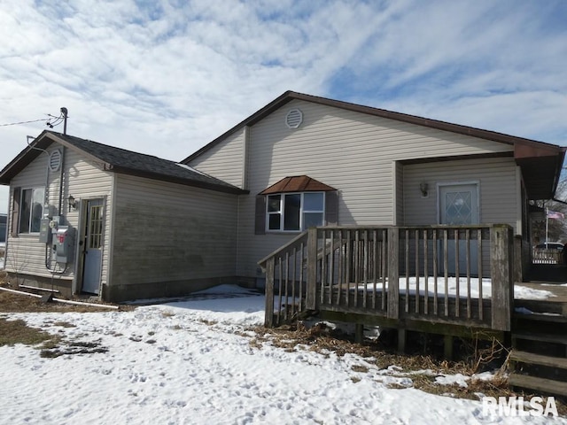 snow covered rear of property with a wooden deck