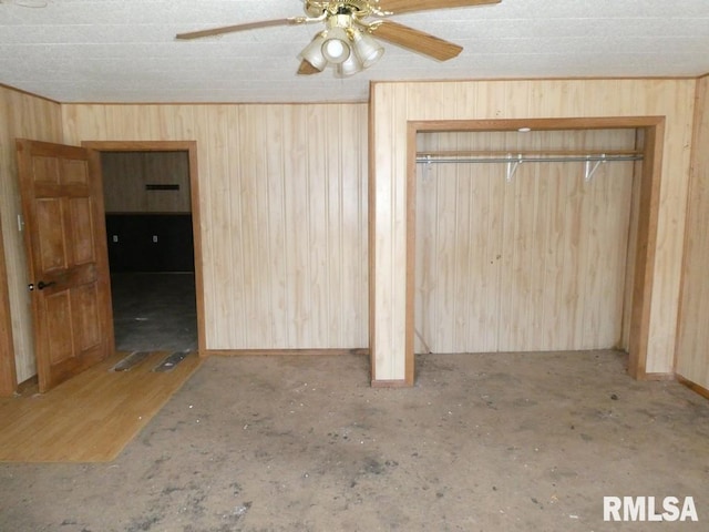 unfurnished bedroom with ceiling fan, a closet, and wood walls