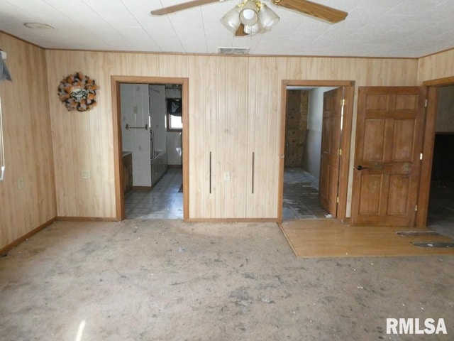 empty room featuring ceiling fan and wood walls