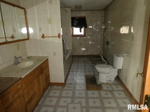 full bathroom featuring washtub / shower combination, vanity, toilet, and tile walls