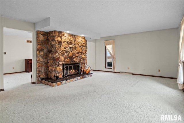 unfurnished living room featuring a stone fireplace, carpet floors, and a textured ceiling