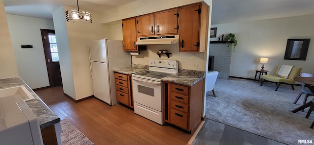 kitchen with a brick fireplace, white appliances, decorative light fixtures, and light wood-type flooring