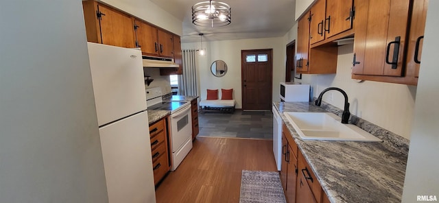 kitchen with pendant lighting, sink, white appliances, and dark wood-type flooring