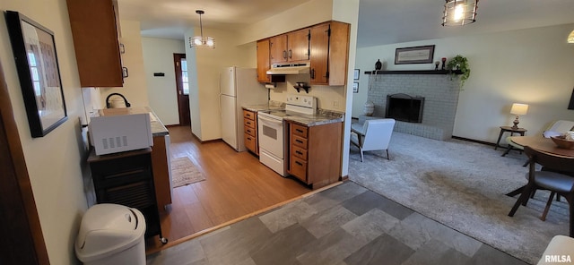 kitchen with pendant lighting, white appliances, a fireplace, and light colored carpet