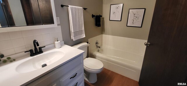 bathroom featuring decorative backsplash, hardwood / wood-style flooring, vanity, a washtub, and toilet