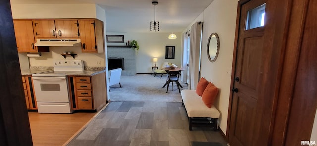 kitchen featuring light hardwood / wood-style flooring, a fireplace, white range with electric stovetop, and decorative light fixtures