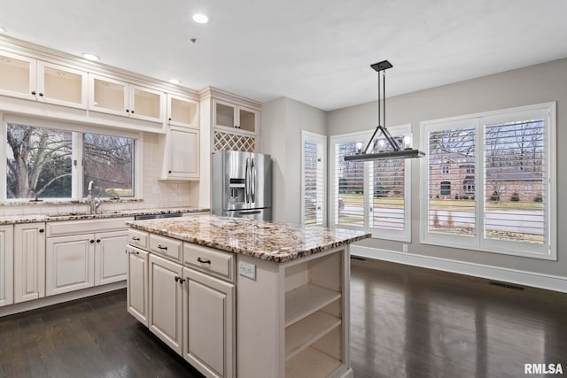 kitchen featuring stainless steel refrigerator with ice dispenser, decorative light fixtures, dark hardwood / wood-style floors, a kitchen island, and decorative backsplash