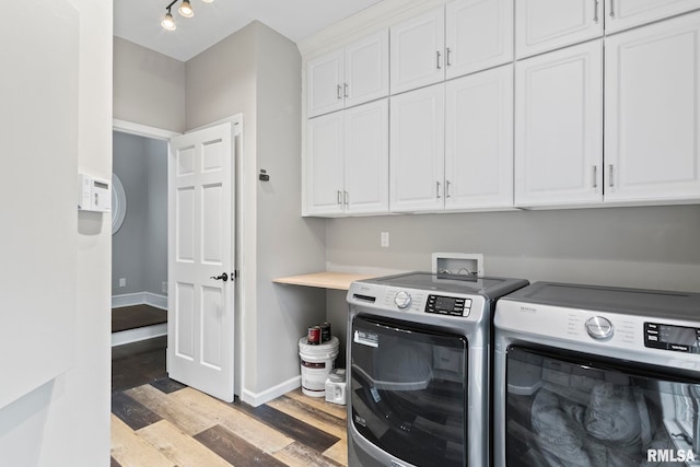 clothes washing area featuring separate washer and dryer, light hardwood / wood-style flooring, and cabinets