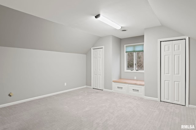 bonus room with vaulted ceiling and light colored carpet