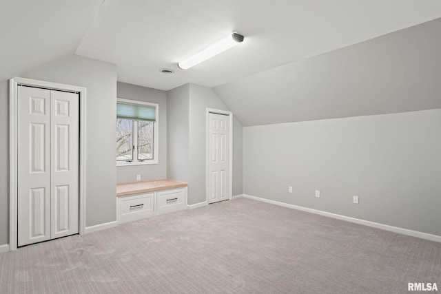 bonus room with lofted ceiling and light carpet