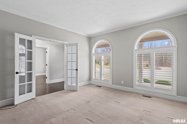 carpeted spare room with plenty of natural light, ornamental molding, and french doors