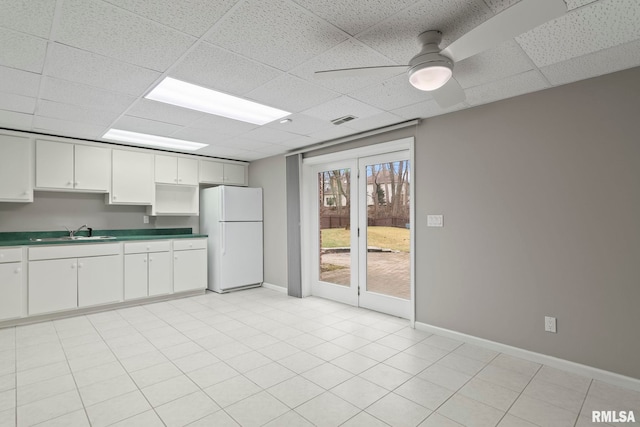 kitchen with sink, ceiling fan, white cabinets, a drop ceiling, and white fridge