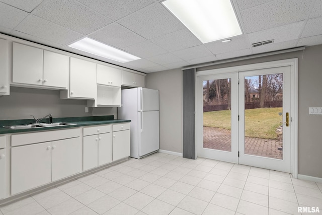 kitchen featuring white refrigerator, white cabinetry, sink, and a paneled ceiling