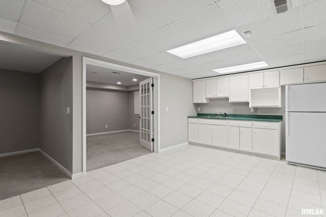 kitchen with white refrigerator, sink, light carpet, and white cabinets