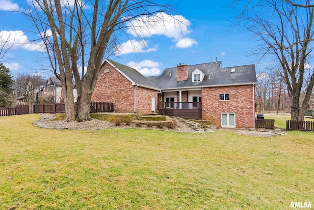 rear view of house with a wooden deck and a lawn