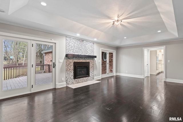 unfurnished living room with dark hardwood / wood-style flooring, a fireplace, and a raised ceiling