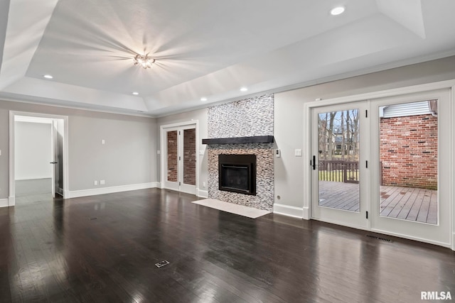 unfurnished living room with a fireplace, dark hardwood / wood-style flooring, and a raised ceiling