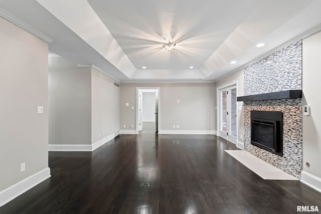 unfurnished living room featuring a tray ceiling, dark wood-type flooring, and a tile fireplace