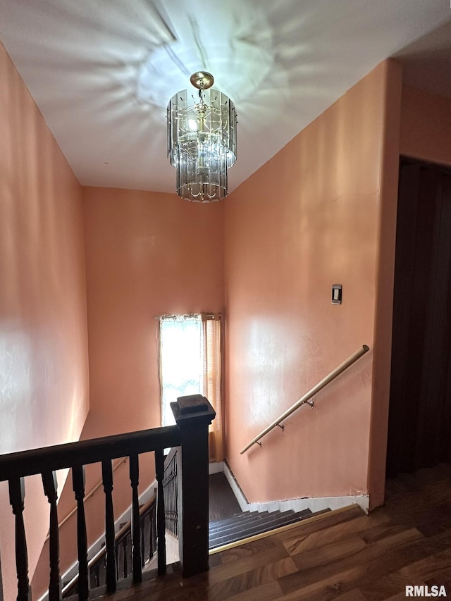 staircase with a notable chandelier and wood finished floors