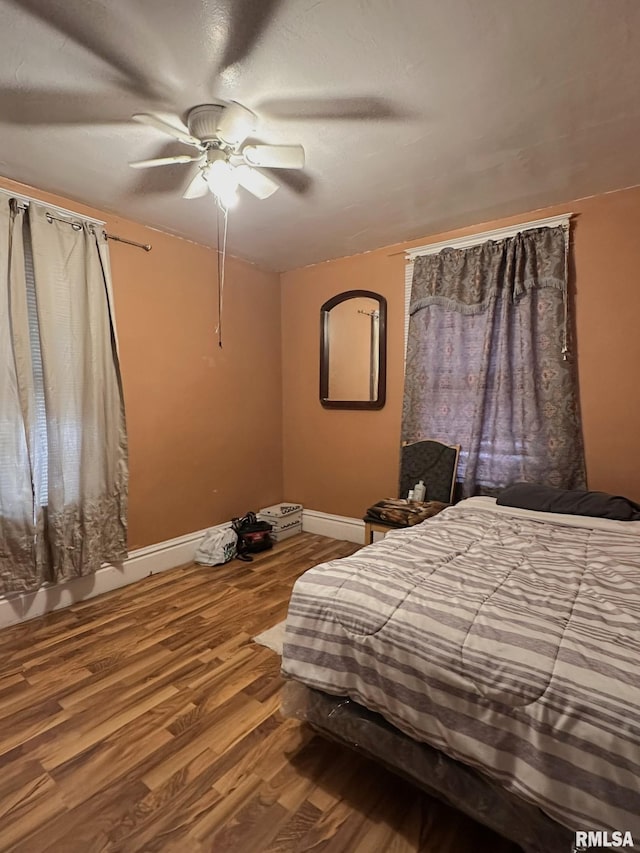 bedroom with ceiling fan, a textured ceiling, baseboards, and wood finished floors