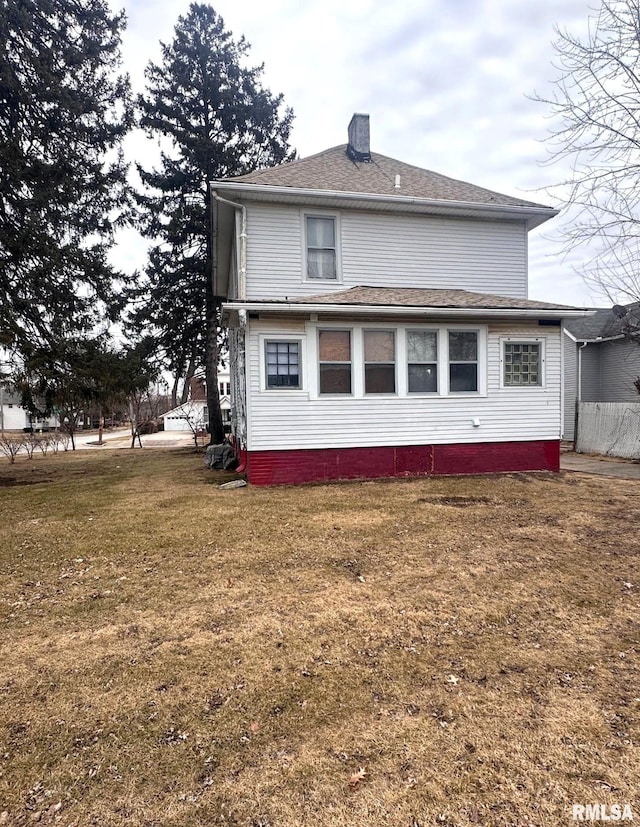 back of house with a chimney and a lawn