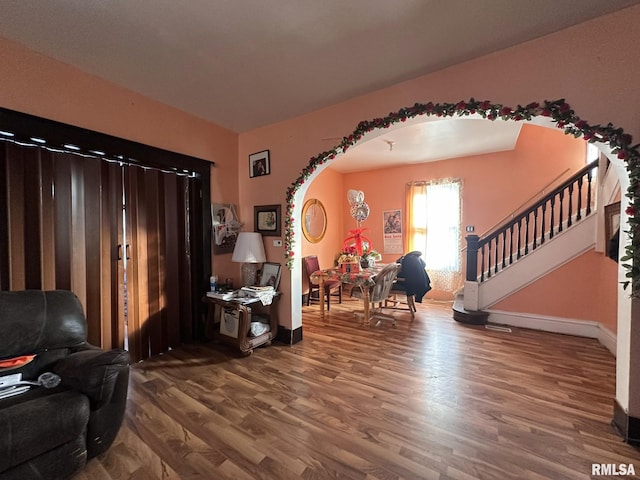 foyer entrance featuring arched walkways, stairway, wood finished floors, and baseboards